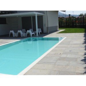 Area piscina con piastrelle in pietra naturale grigio chiaro (t.b.t.) e acqua turchese.