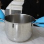Pentola con presine in silicone blu sui manici. Utensile da cucina per cucinare in sicurezza.
