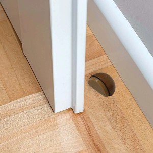 Fermaporta (Fermaporte) marrone, semicircolare, sul pavimento davanti a un telaio di porta bianco.
