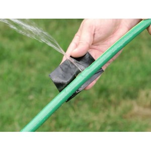 Tubo da giardino riparato con nastro sigillante nero. L'acqua schizza dal foro.