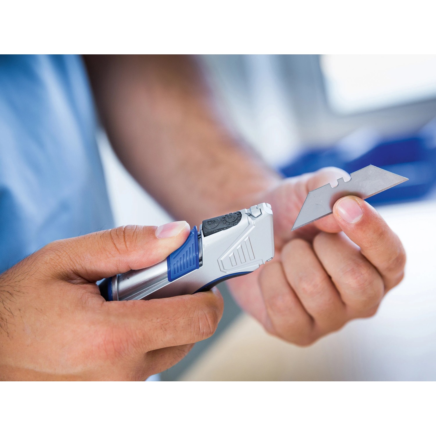 Cutter LUX con custodia e lama in mano, argento con manico blu.