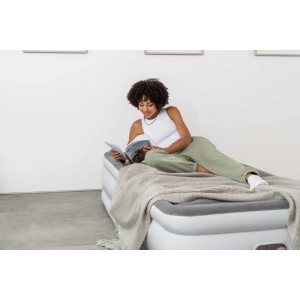 Donna legge su letto ad aria t.b.t.. Attrezzatura da campeggio per notti rilassanti.