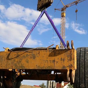Cinghia di fissaggio t.b.t. che solleva un carico giallo con gru sullo sfondo.