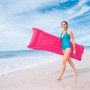 Donna con materassino gonfiabile rosa sulla spiaggia.
