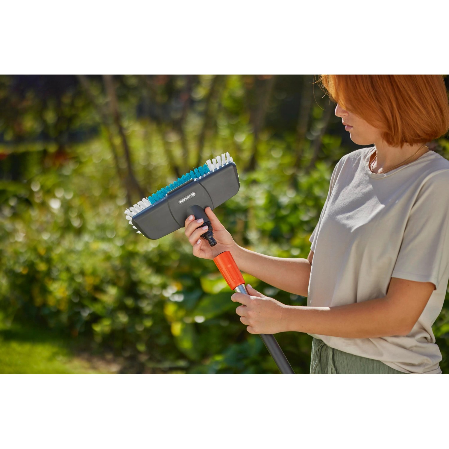 Spazzola Gardena Cleansystem Hard antracite con donna in giardino. Ideale per la pulizia a umido.