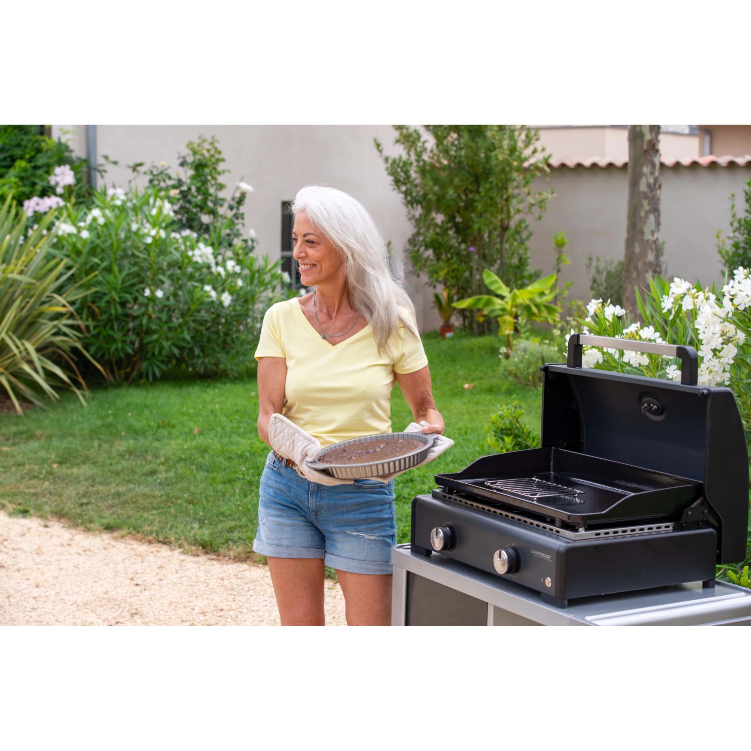 Donna con torta al barbecue da campeggio t.b.t. in giardino.