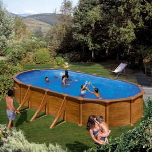 Piscina ovale Gre Mauritius effetto legno in giardino, famiglia che nuota.