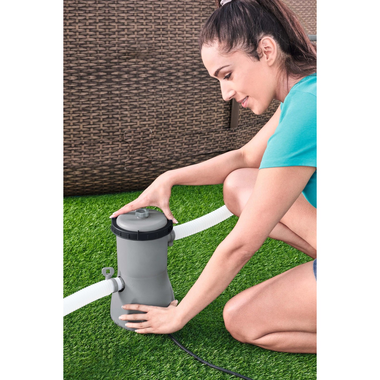 Donna installa sistema di filtro a cartuccia grigio su prato. Accessorio per piscina.