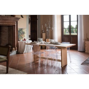 Tavolo in legno con sedie trasparenti in una sala da pranzo con Ripiani in legno.