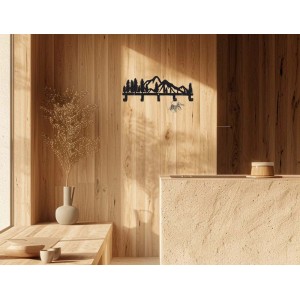 Portachiavi nero con motivo di montagna e foresta su parete in legno.