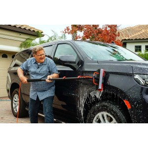 Uomo lava auto con spazzola e acqua. Cura dell'auto facilitata.