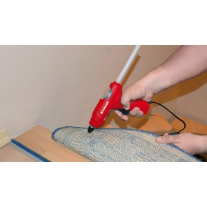 Pistola per colla a caldo Einhell TC-GG 30 rossa e nera in uso su un tappeto.
