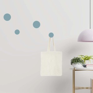 Appendiabiti t.b.t. con borsa di stoffa su parete con tavolo e lampada.