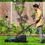 Uomo taglia prato con tagliaerba elettrico Bosch Easy Rotak 32-215 verde-nero in giardino recintato.