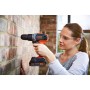 Donna che fora muro di mattoni con trapano avvitatore a percussione Black+Decker BCD003 18V.