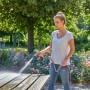 Donna pulisce tavolo con Gardena Comfort Cleaning Sprayer ecoPulse™ in giardino.