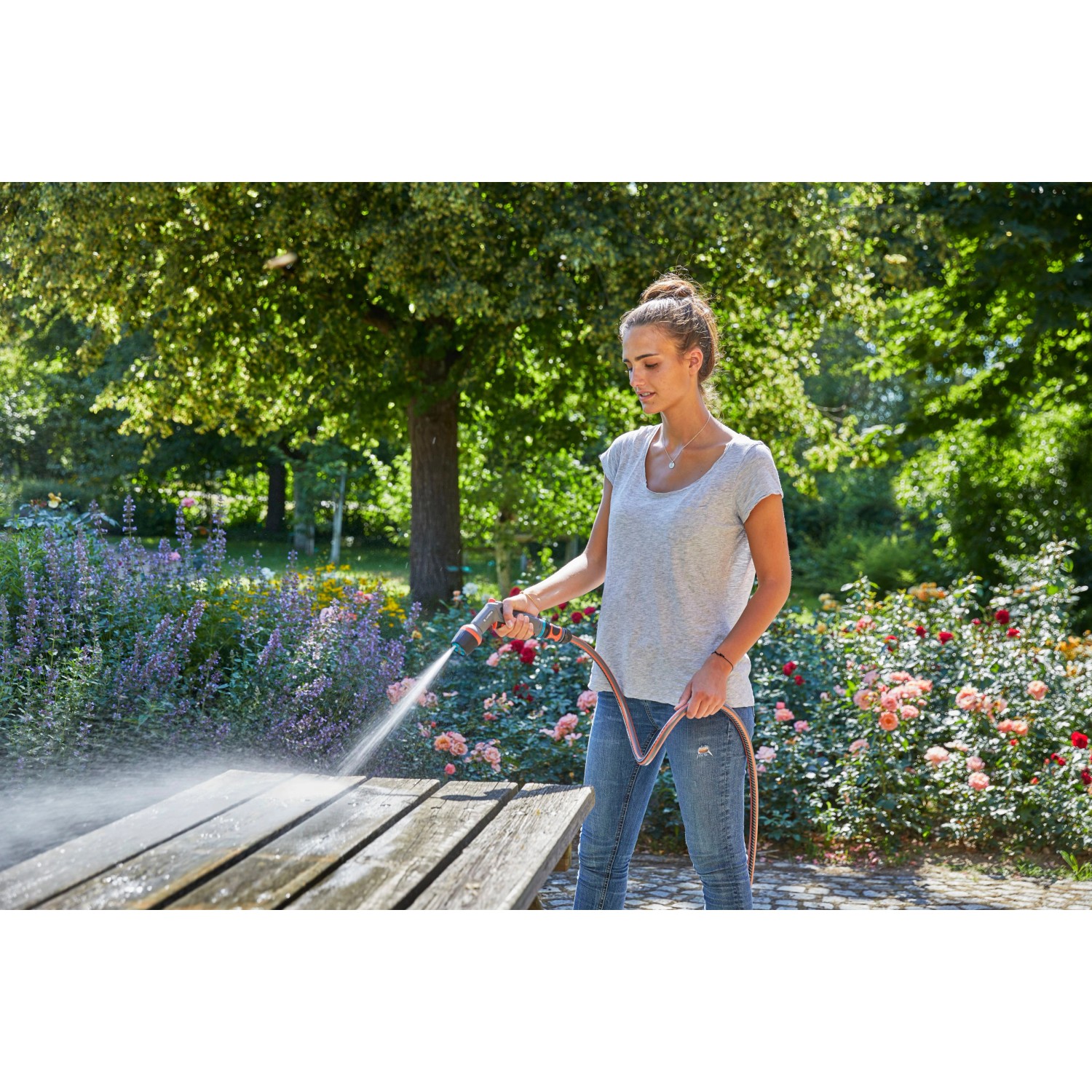 Donna pulisce tavolo con Gardena Comfort Cleaning Sprayer ecoPulse™ in giardino.