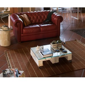 Soggiorno con tavolino da caffè su pallet e piano in vetro.