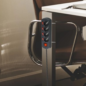 Multipresa grigia t.b.t. con quattro prese e interruttori rossi sulla scrivania.