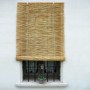 Tenda a rullo in bambù naturale davanti a una finestra. Protezione della privacy per interni.