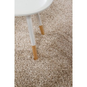 Dettaglio di un tappeto a pelo lungo beige con gambe di tavolo. Tappeto morbido per spazi abitativi.