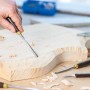 Mano che intaglia il legno con il set di intaglio LUX da 11 pezzi. Include coltelli, scalpelli e pietra per affilare.