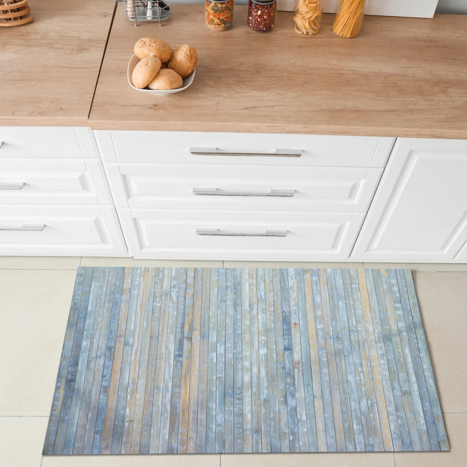 Tappeto da cucina blu effetto legno davanti a mobili da cucina bianchi.