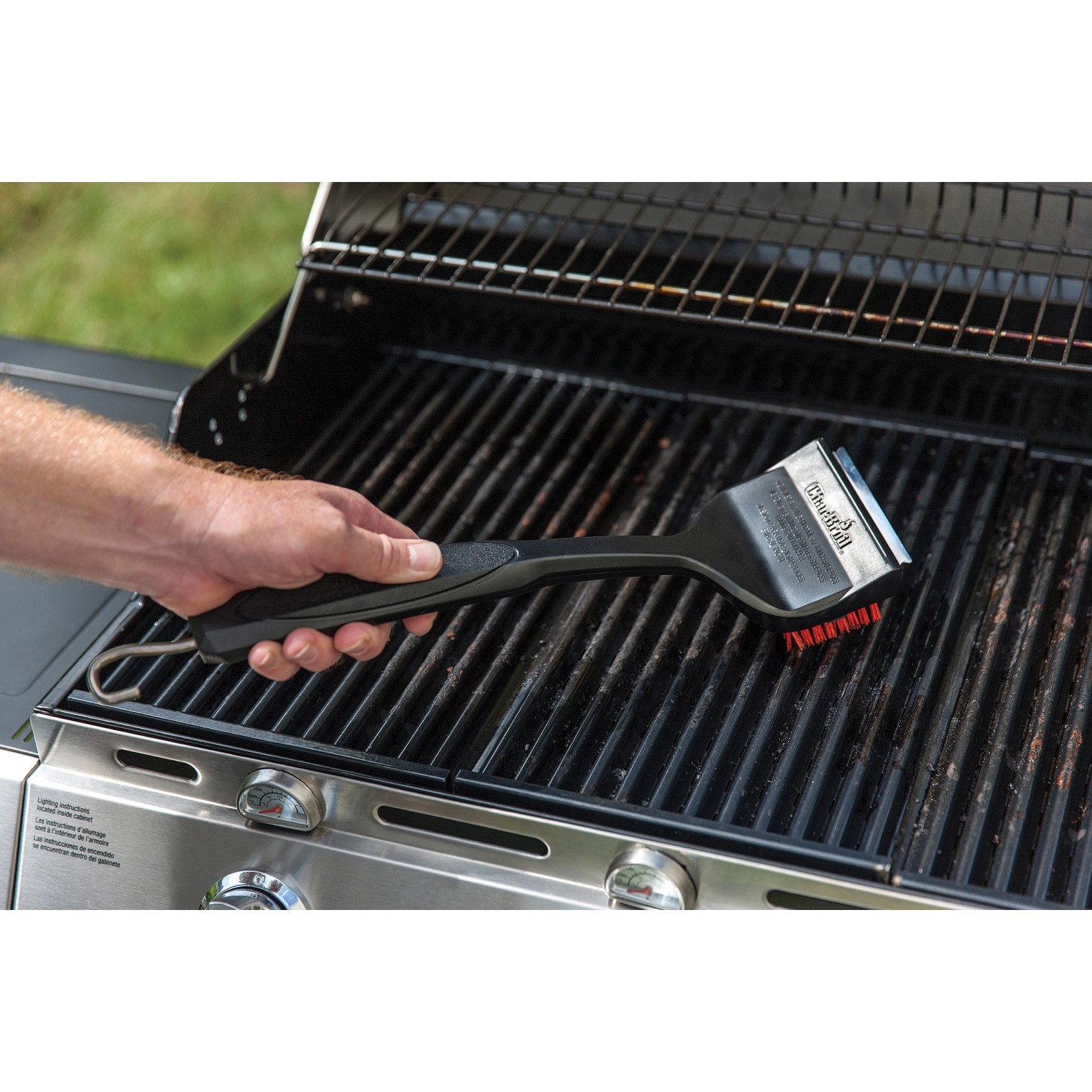 Spazzola per griglia Char-Broil Cool Clean Premium in azione su griglia. Utensile per barbecue con raschietto e gancio.