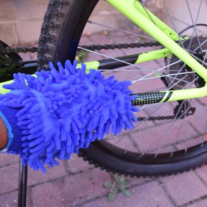 Guanto spazzola in microfibra blu che pulisce una bicicletta. Accessorio pratico per la cura della bici.