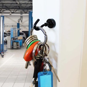Gancio magnetico nero con portachiavi su una porta bianca in un'officina.