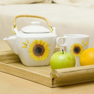 Teiera e tazza con adesivo murale girasole su vassoio.