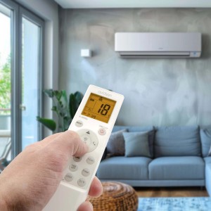 Mano che aziona il condizionatore d'aria con telecomando in soggiorno.