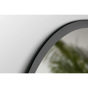 Dettaglio di uno specchio da parete rotondo con cornice sottile e scura.