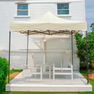 Gazebo beige con tavolo e sedie su una terrazza in legno bianco davanti a una casa bianca.