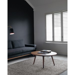 Soggiorno con tappeto a pelo lungo t.b.t. grigio, divano e tavolo rotondo in legno.