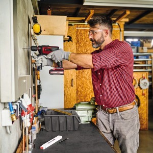 Uomo che fora con trapano a percussione a batteria Einhell TE-ID 18 Li - Solo in officina.