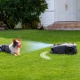 Robot tagliaerba su prato con cane. Il t.b.t. assicura un giardino ben curato.