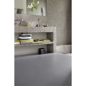Pavimento vinilico t.b.t. grigio in bagno con parete in pietra e asciugamani.