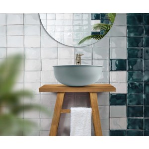 t.b.t. Lavabo d'appoggio azzurro chiaro su consolle in legno davanti a parete piastrellata.