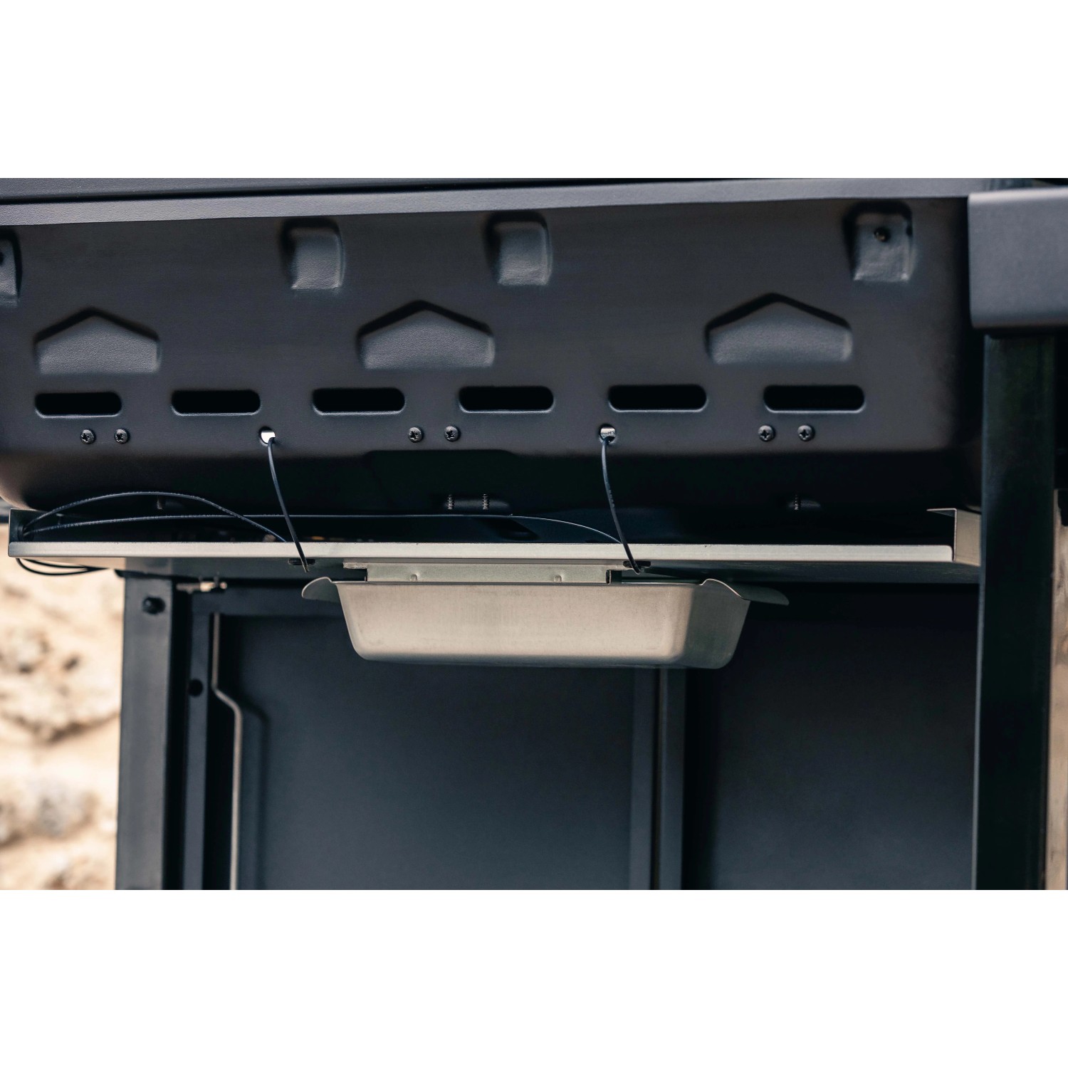 Dettaglio di un barbecue a gas con vaschetta raccogli grasso sotto la zona cottura.