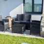Set di mobili da giardino in rattan nero con divano, poltrone e tavolo.