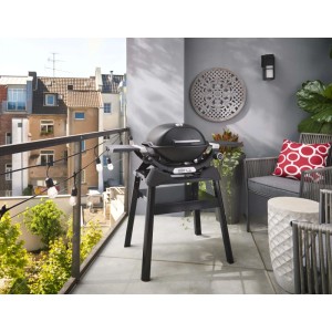 Barbecue a gas t.b.t. nero su un balcone con mobili da barbecue.