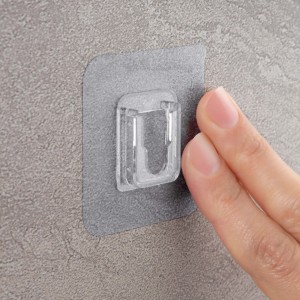 Supporto adesivo trasparente per accessori doccia fissato a parete grigia.