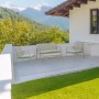 Set mobili da giardino t.b.t.: divano, due sedie e tavolo su terrazza con vista montagna.