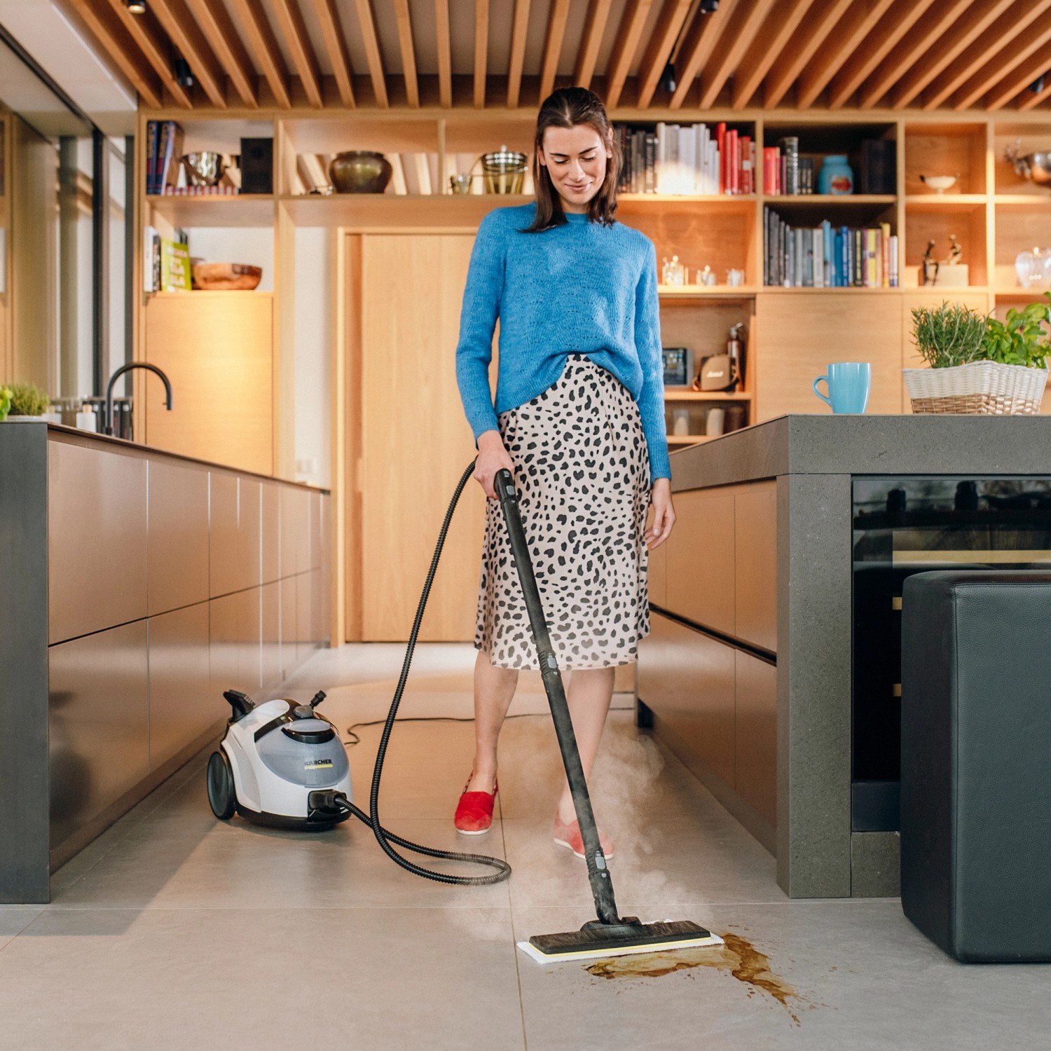 Donna pulisce pavimento piastrellato con il pulitore a vapore Kärcher SC 5 EasyFix Iron Plug in cucina.