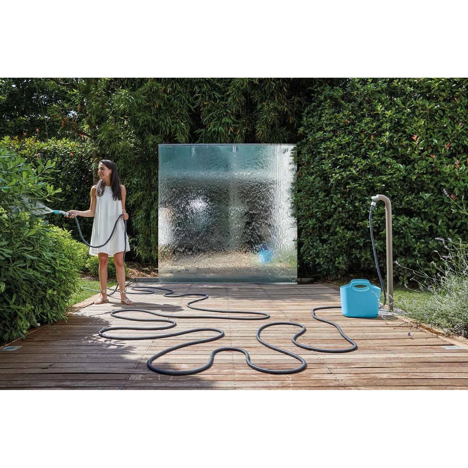 Donna che annaffia le piante con un tubo per irrigazione t.b.t. in giardino.
