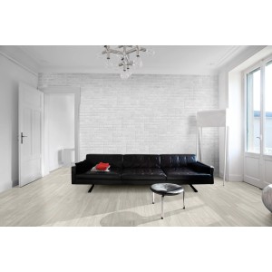 Soggiorno con piastrelle da rivestimento t.b.t. bianche effetto mattone dietro un divano nero.