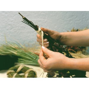Mani che legano un bouquet con rafia naturale. Rafia color naturale per decorazioni e giardinaggio.