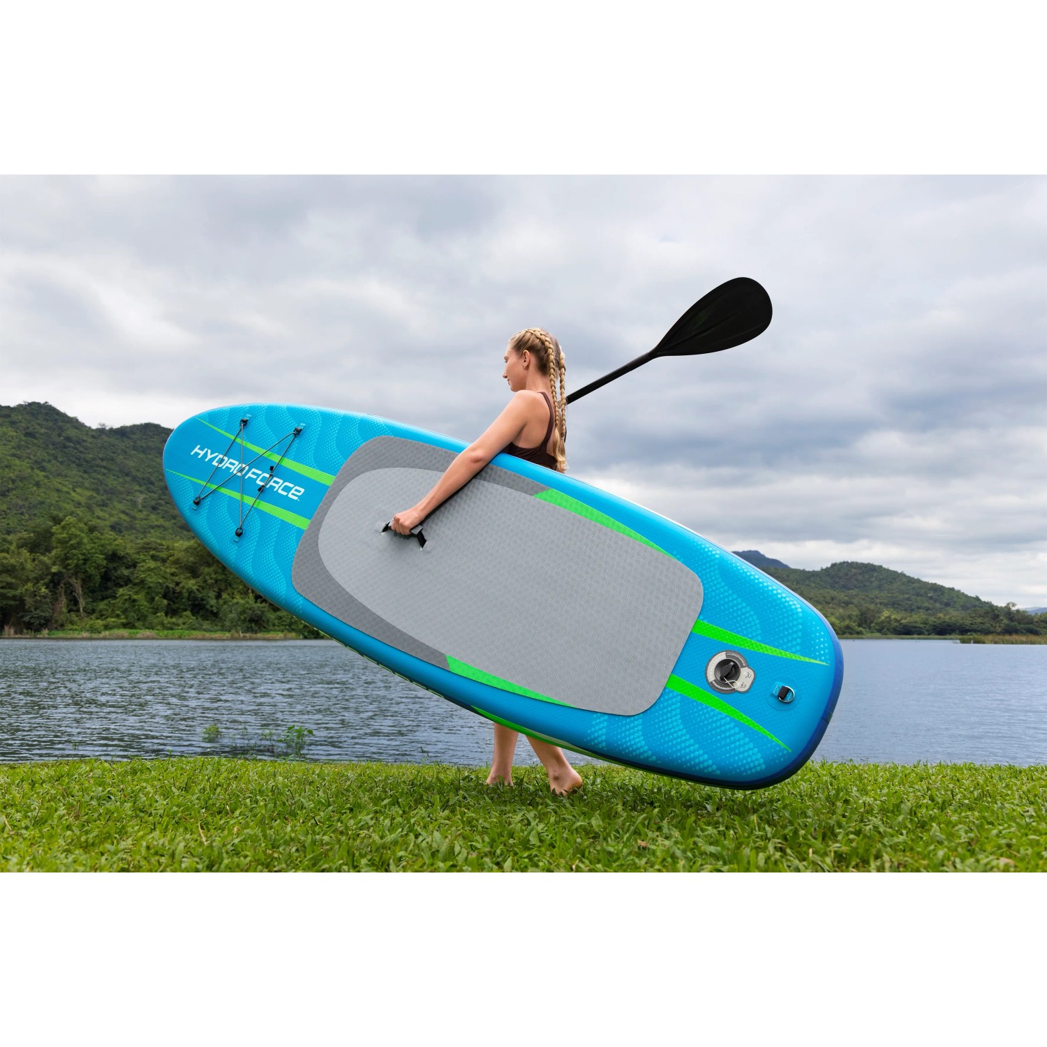 Donna che trasporta la tavola SUP Allround Bestway Aqua Journey blu con pagaia al lago.