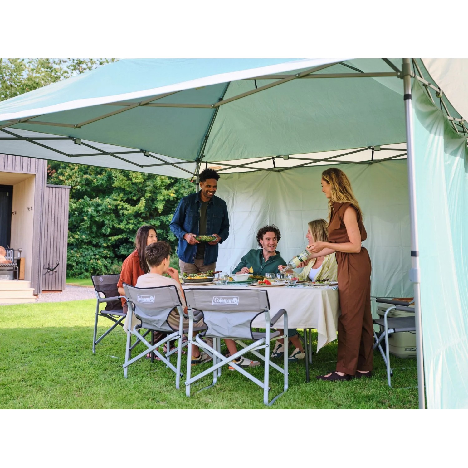 Coleman FastPitch OnePush Shelter L verde e bianco in campeggio con persone.
